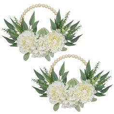 two white flowers and greenery are arranged in the shape of wreaths with beads