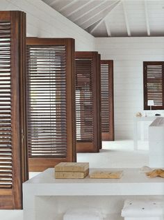 the interior of a white room with wooden shutters