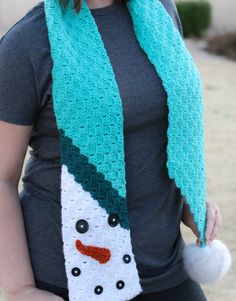 a woman wearing a crocheted snowman scarf