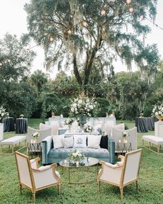 an outdoor seating area with couches, chairs and tables in front of a large tree