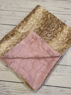 a pink and brown blanket sitting on top of a wooden floor