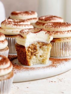 cupcakes with white frosting and cinnamon sprinkles on a plate