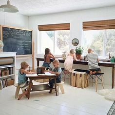 two children sitting at a table in front of a blackboard