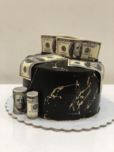 a cake with money sitting on top of it next to two rolls of paper currency