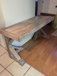 a wooden bench sitting on top of a hard wood floor next to a door way