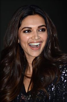 an image of a woman smiling with long hair and brown eyeshadow on her face