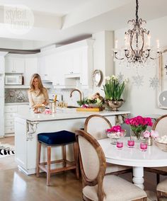 a woman is sitting at the kitchen counter in front of a chandelier and table