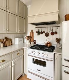 a white stove top oven sitting inside of a kitchen next to wooden spoons and utensils