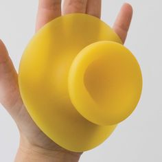 a hand holding a yellow plastic object in the palm of it's left hand