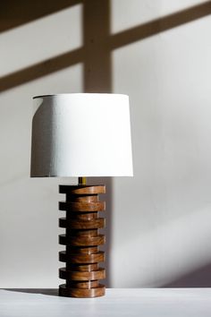 a lamp that is sitting on top of a white table next to a window with the light coming through it