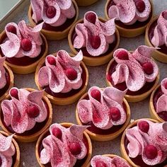 many cupcakes with pink frosting and cherries on them are arranged in rows