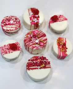 nine decorated cakes sitting on top of a white table next to each other with pink and red decorations