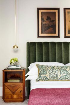 a bed with green headboard and two pictures on the wall above it in a bedroom