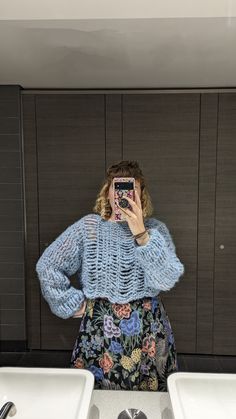 a woman taking a selfie in front of two sinks with her cell phone up to her face