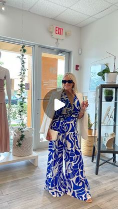 a woman in a blue and white dress standing next to a mannequin holding an umbrella