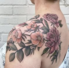 a woman's shoulder with flowers and leaves on it