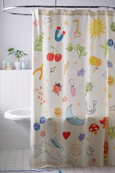 the shower curtain is decorated with colorful cartoon characters and symbols on white tile flooring