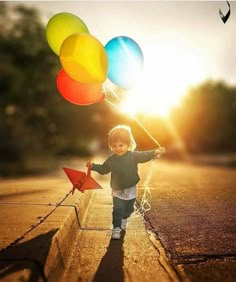 a little boy holding onto some colorful balloons