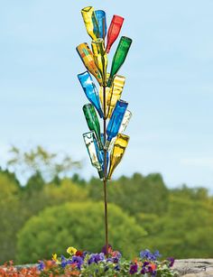 a multicolored glass wind chime on top of a rock in front of some flowers