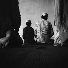 three men sitting on the floor in front of a wall and one man is wearing a turban