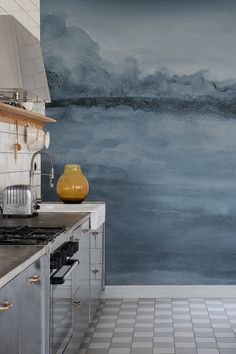 a kitchen with blue and gray wallpaper, stainless steel appliances and white tile flooring