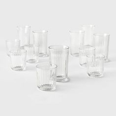 a set of nine clear glass tumblers on a white surface with no one in the photo