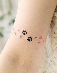 a small tattoo on the arm of a woman's leg with flowers and leaves