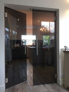 an open glass door leading to a kitchen and living room with wood floors in the background