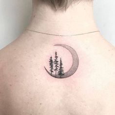 the back of a woman's shoulder with a crescent moon and trees on it