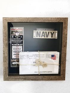 an envelope is tied up and placed in a shadow box with the us navy license plate on it