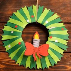 a paper wreath with a lit candle hanging from the front on a wooden surface,