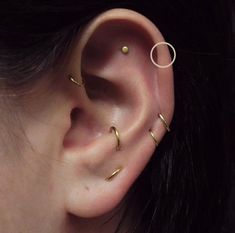 a close up of a person's ear with two gold piercings on it