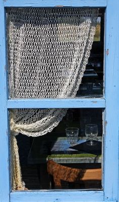 a cat sitting on the window sill in front of a table with wine glasses