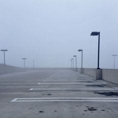 an empty parking lot with street lights in the fog