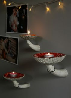 two white birds holding red plates with lit candles