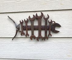 an old rusty wrench hanging on the side of a white house with wood siding