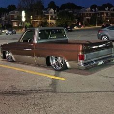 a brown and silver truck parked in a parking lot next to other cars at night