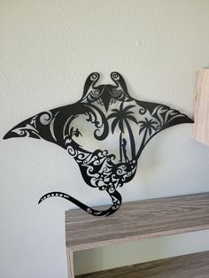 a metal bird sculpture sitting on top of a wooden shelf next to a white wall