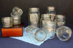 there are many mason jars and lids on the table top, including one with a wooden base