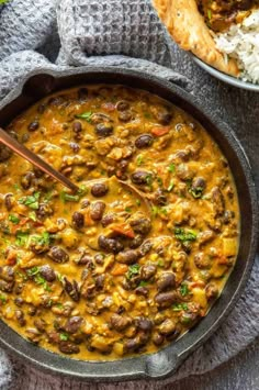 a skillet filled with beans and rice next to a bowl of bread on the side