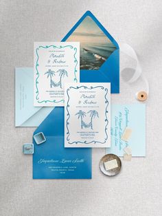 the wedding stationery is set up with blue and white cards, envelopes, and wax stamp