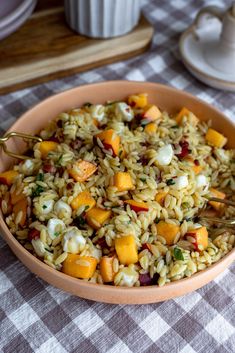 a bowl filled with rice and vegetables on top of a checkered tablecloth covered table