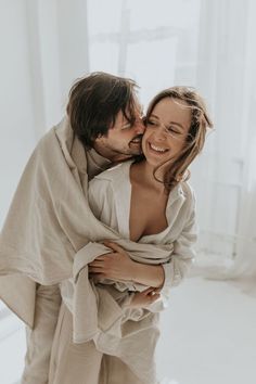 a man and woman embracing each other while wrapped in a blanket