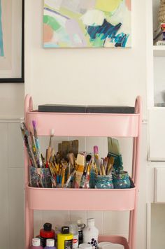 a pink cart filled with lots of paint and brushes