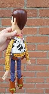 a hand is holding a toy with a cowgirl outfit and cowboy boots on it