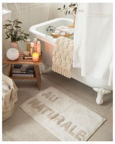 a bathroom with a bathtub, rugs and candles on the floor next to it