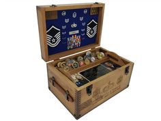 an open wooden box with buttons and medals in it on a white background, showing the contents inside