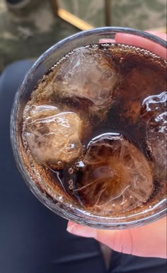 a person holding a glass with ice in it