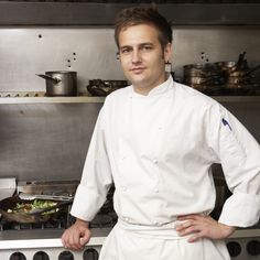 a man standing in front of a stove with pots and pans on it