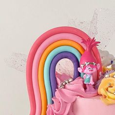 there is a pink cake decorated with rainbows and flowers on the top, along with other decorations